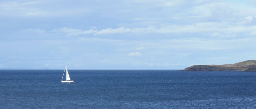Image of a yacht sailing off a headland
